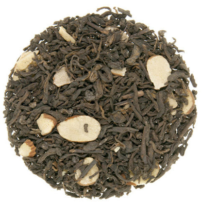 A close-up of black tea leaves with pieces of almond embedded within.